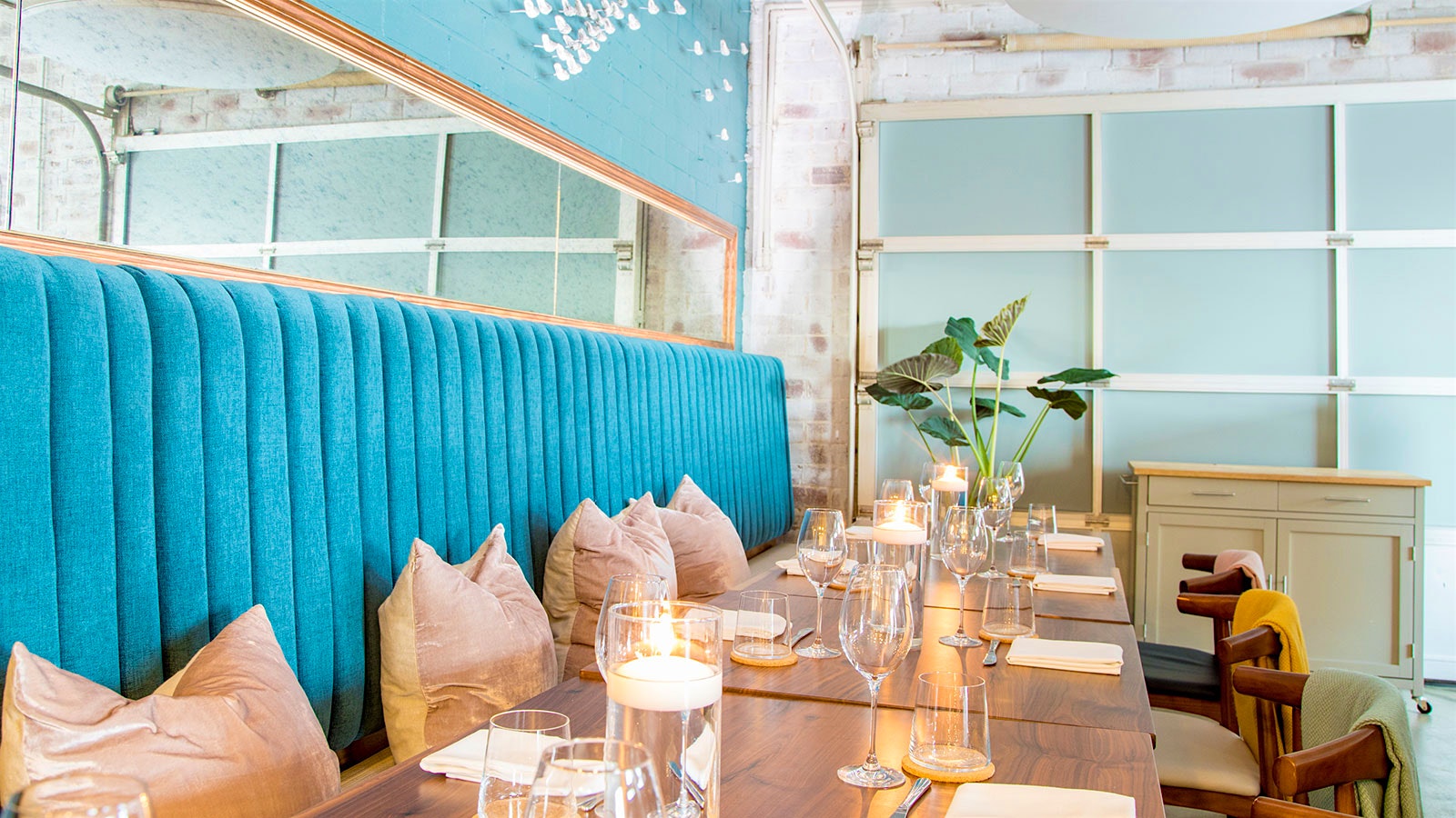The dining room at Lazy Betty, with blue benches, beige pillows, blue and white walls and wooden tables